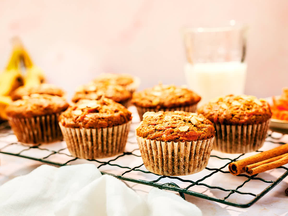 Moist Banana Carrot Muffins topped with oats on a cooking rack.