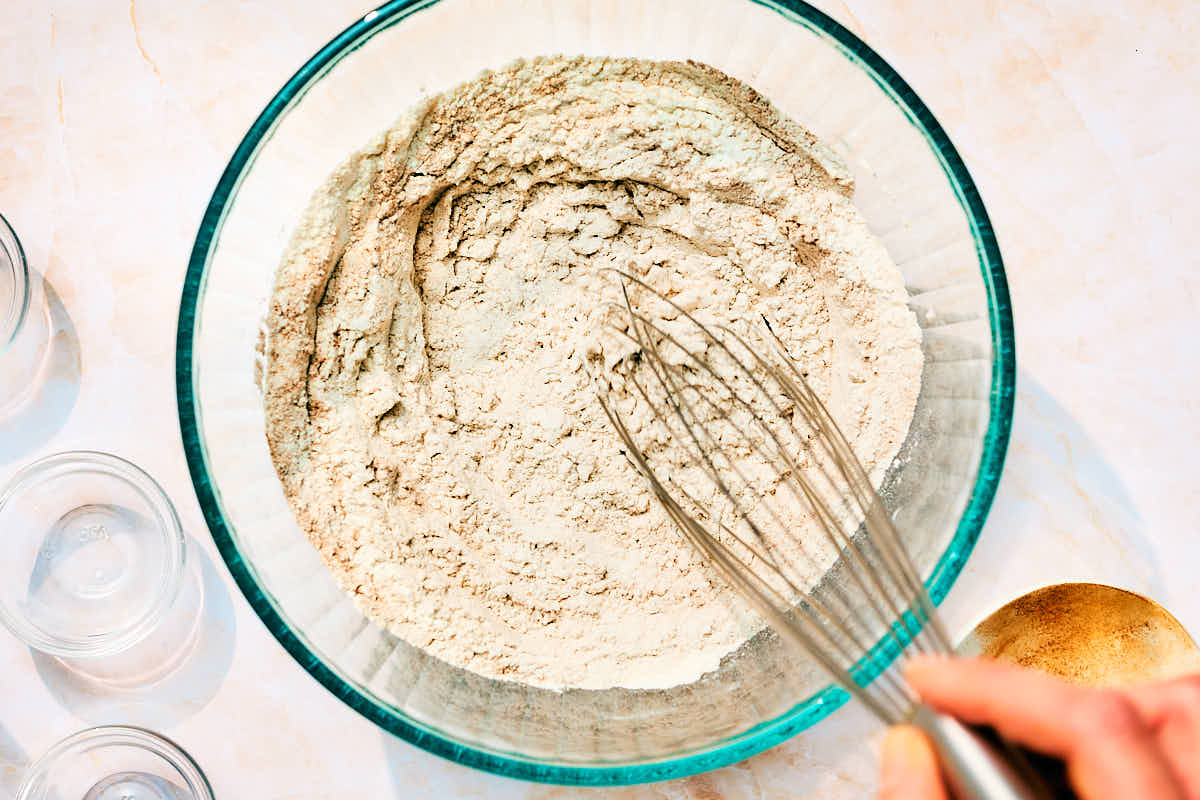 Dry ingredients being whisked in a bowl to make moist egg-free banana carrot muffins.