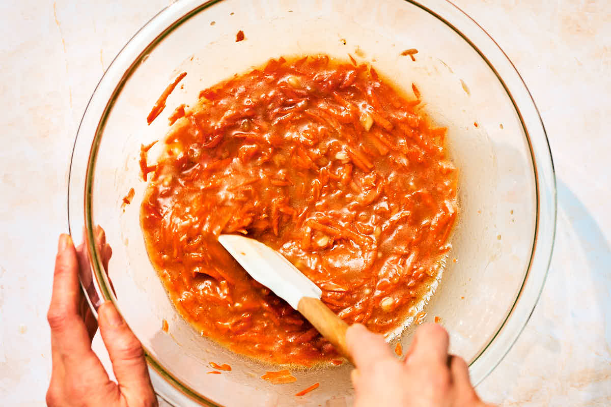 Wet ingredients being mixed in a glass bowl for Banana and Carrot Muffins.