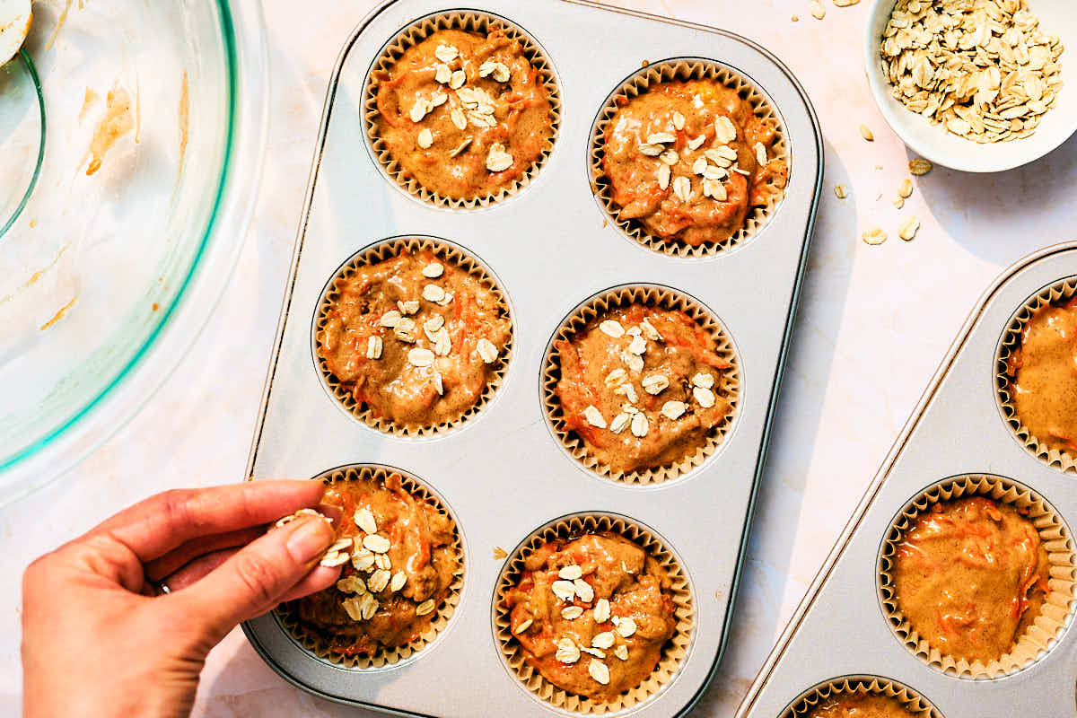 Sprinkling oats over Banana and Carrot muffins without eggs before baking.
