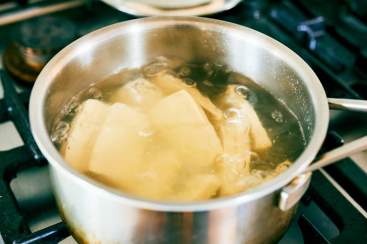 Slices of extra-firm tofu boiling in salted water.