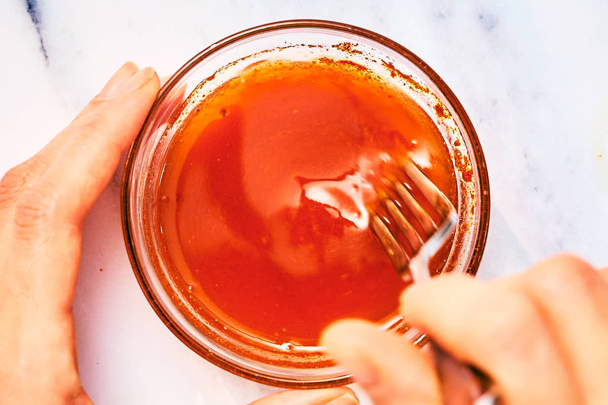 Nashville Hot Oil being mixed in a small glass bowl with a fork.