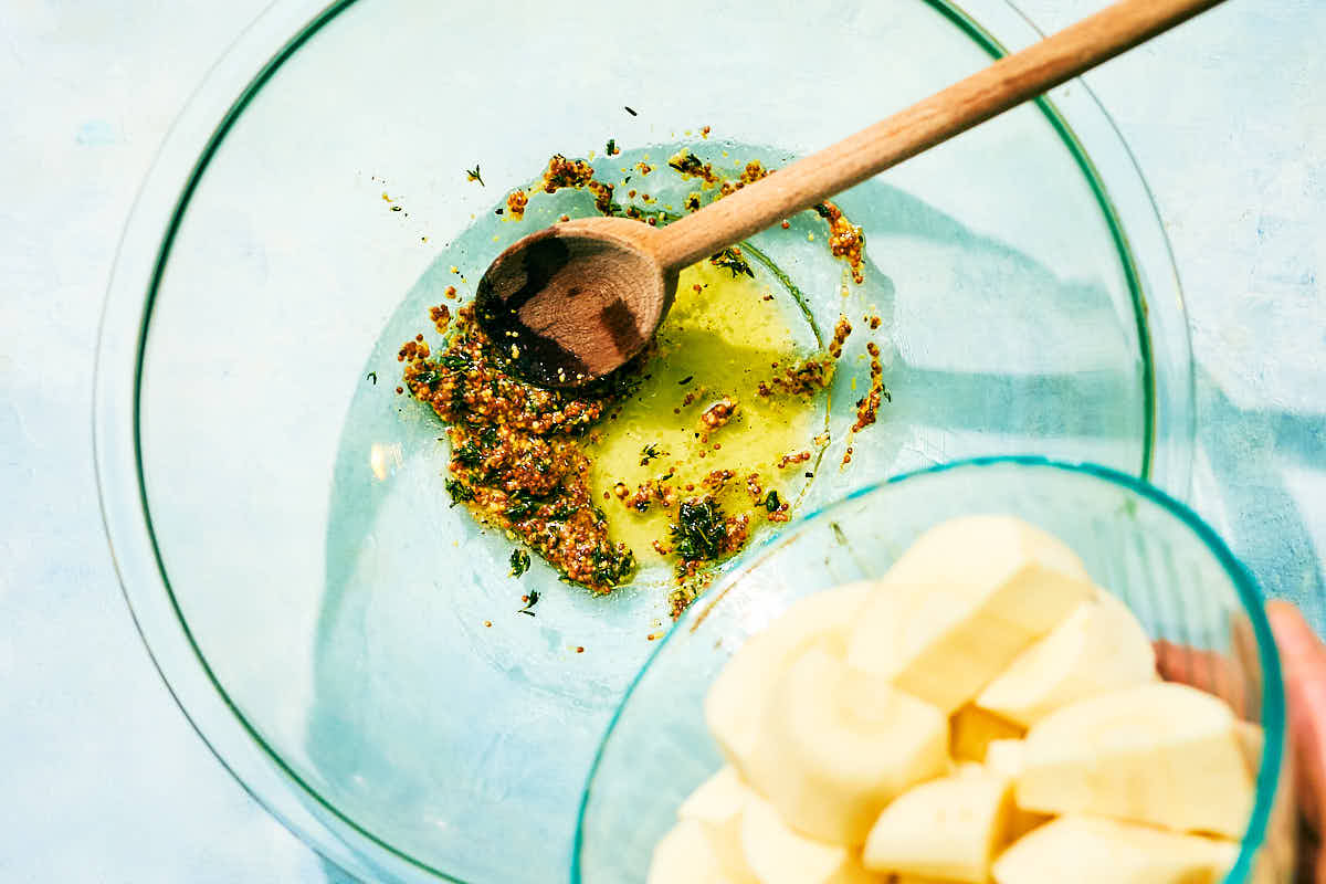 Chopped parsnips being added to a bowl of olive oil and seasonings.