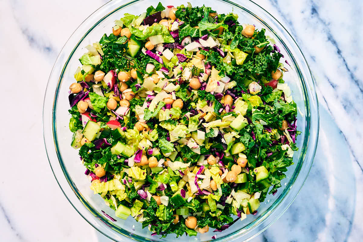 Chopped Dill Pickle Salad with kale and cabbage in a glass bowl.