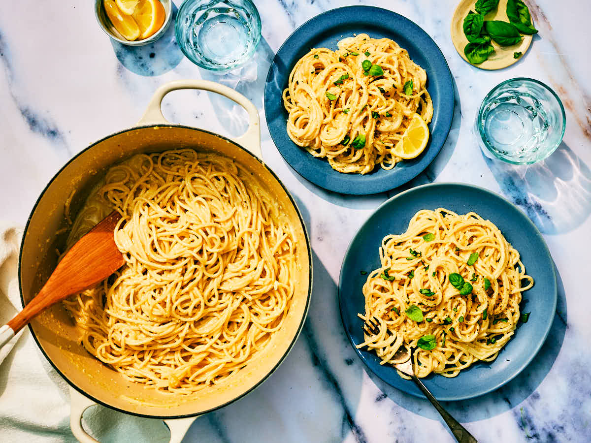 Lemon Pesto Pasta in a pot and on dinner plates on a marble counter.