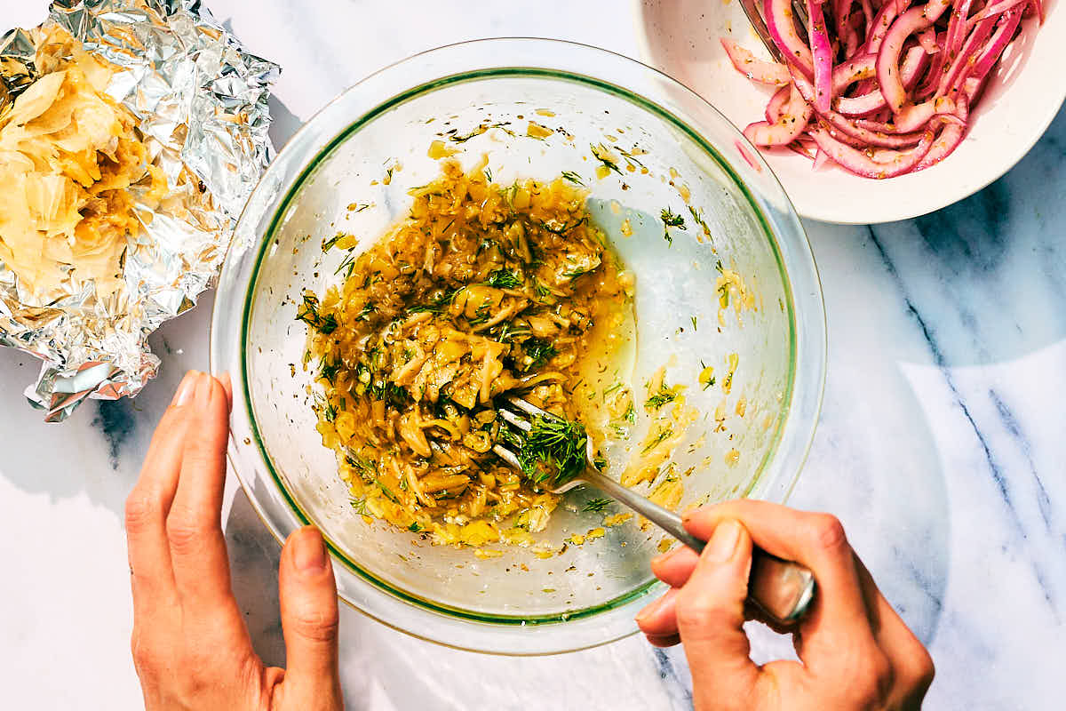 Pepperocini, roasted garlic, dill being whisked in a bowl for pepperocini dressing.