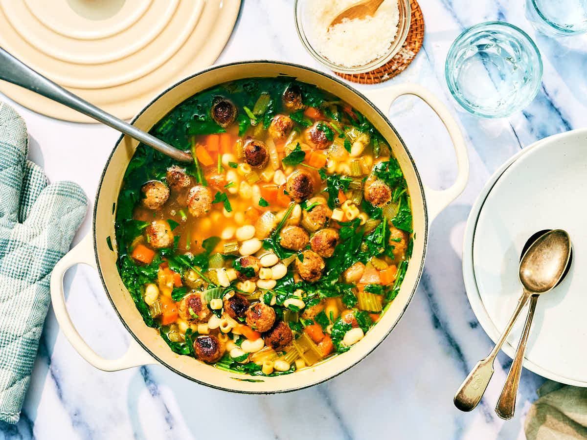 Vegan Italian Wedding Soup in a pot with a serving spoon and bowls.