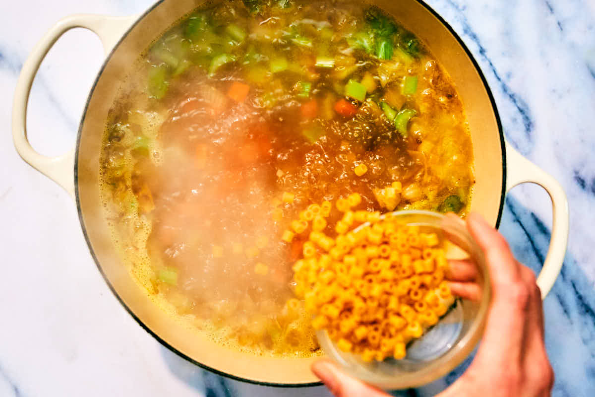 Pasta being added to a pot of vegan Italian Wedding Soup.