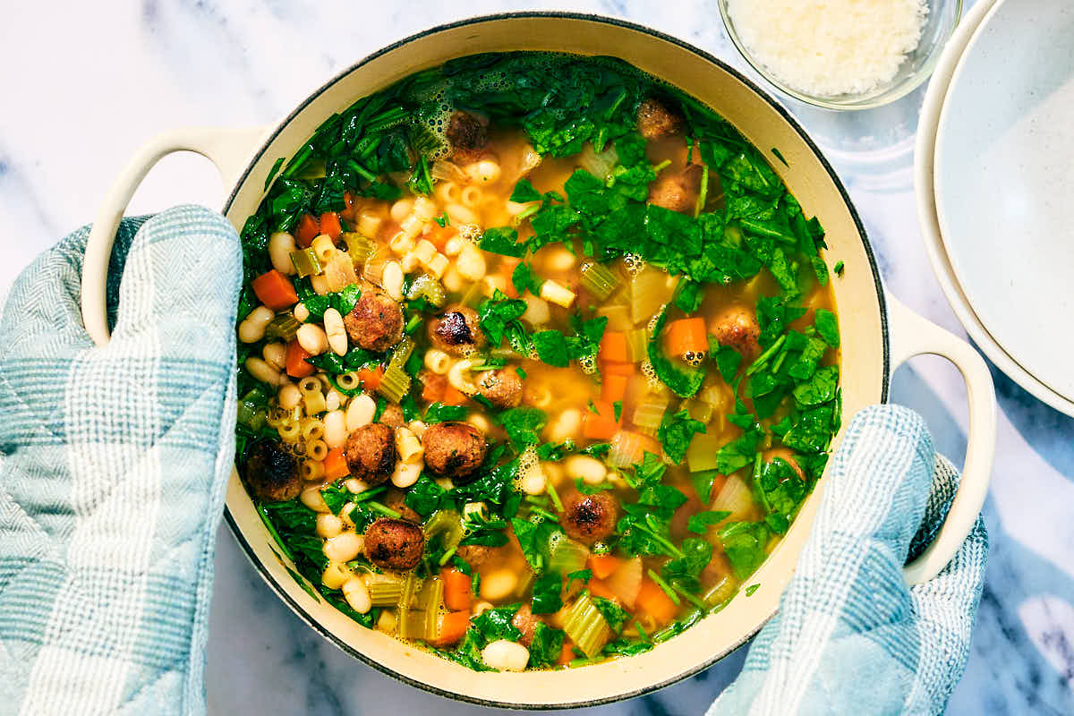 Vegan Italian Wedding Soup with beans and spinach in a pot.