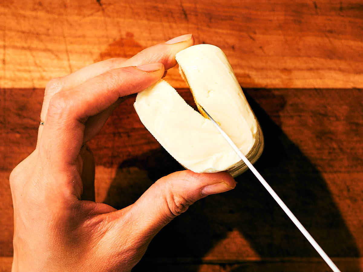 A knife cutting down the natural middle split in a block of halloumi.