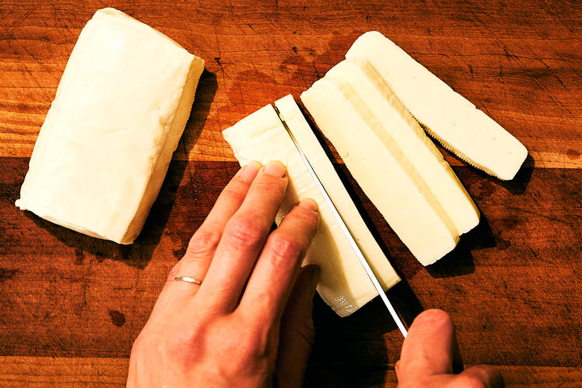 Halloumi cheese being sliced into sticks for Halloumi Fries.
