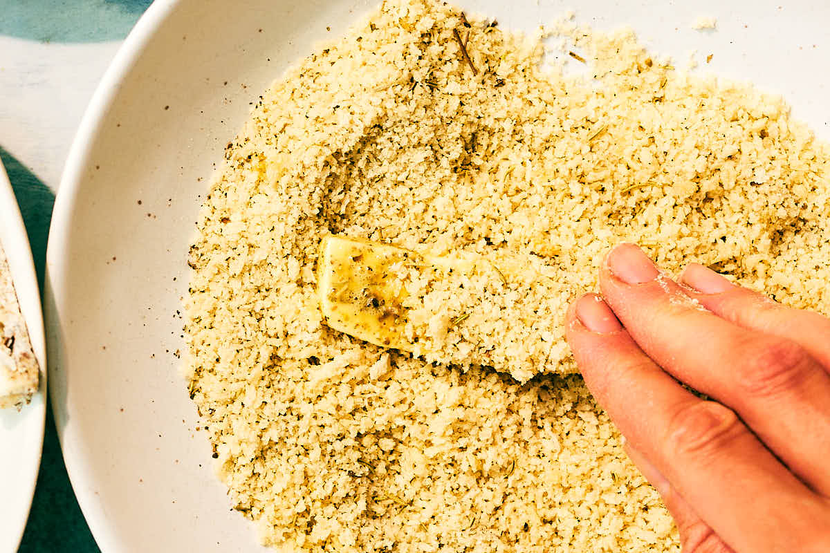 Halloumi fries being coated in panko breadcrumbs before baking.