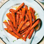 Air Fryer Honey Roasted Carrots with garlic and butter on a serving plate with a spoon.