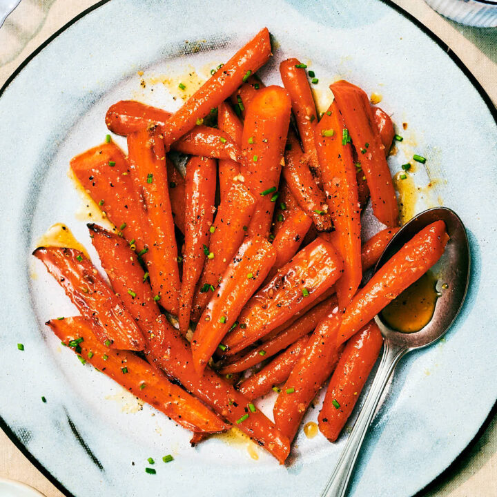Air Fryer Honey Roasted Carrots with garlic and butter on a serving plate with a spoon.