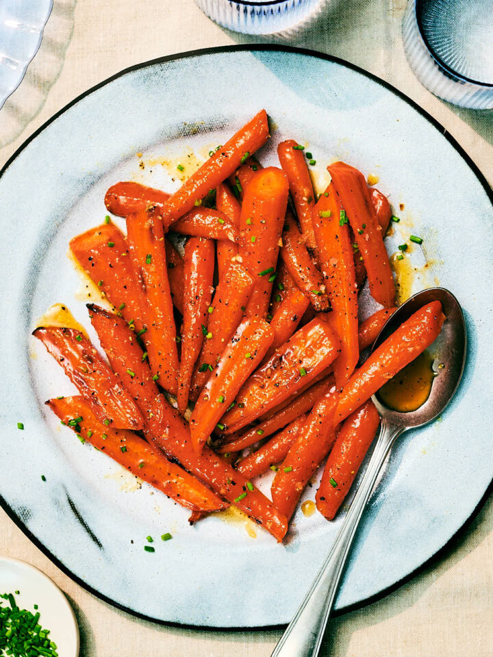 Air Fryer Honey Roasted Carrots with garlic and butter on a serving plate with a spoon.