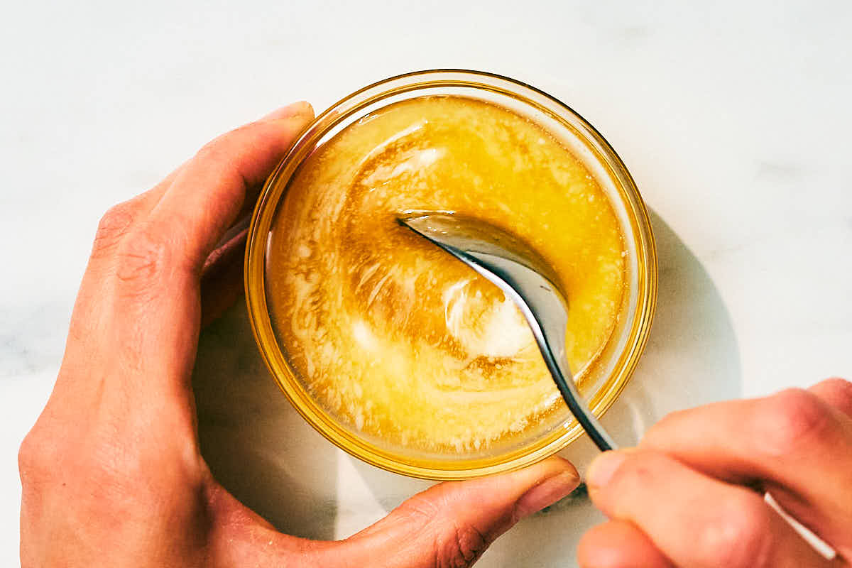 Melted butter and honey being stirred together in a glass bowl.