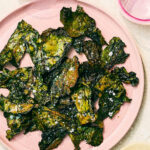Vegan crispy baked Swiss Chard Chips on a pink plate.