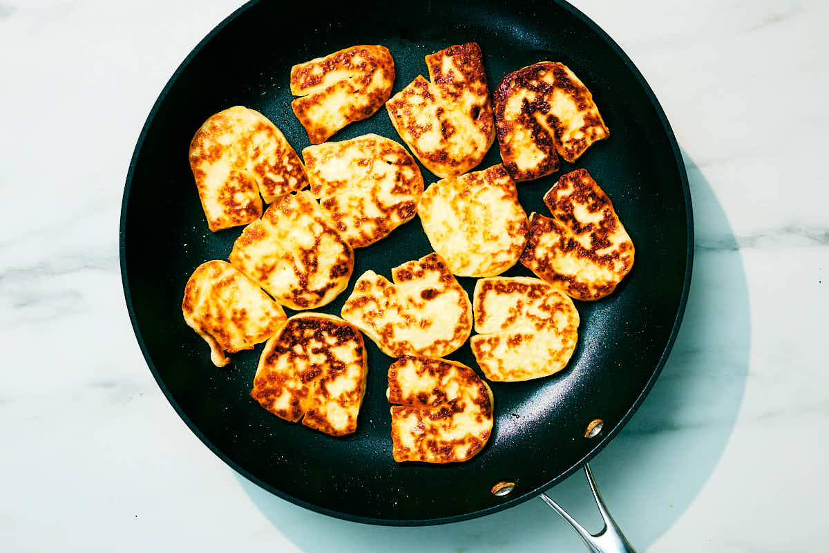 Slices of halloumi cheese seared in a skillet.