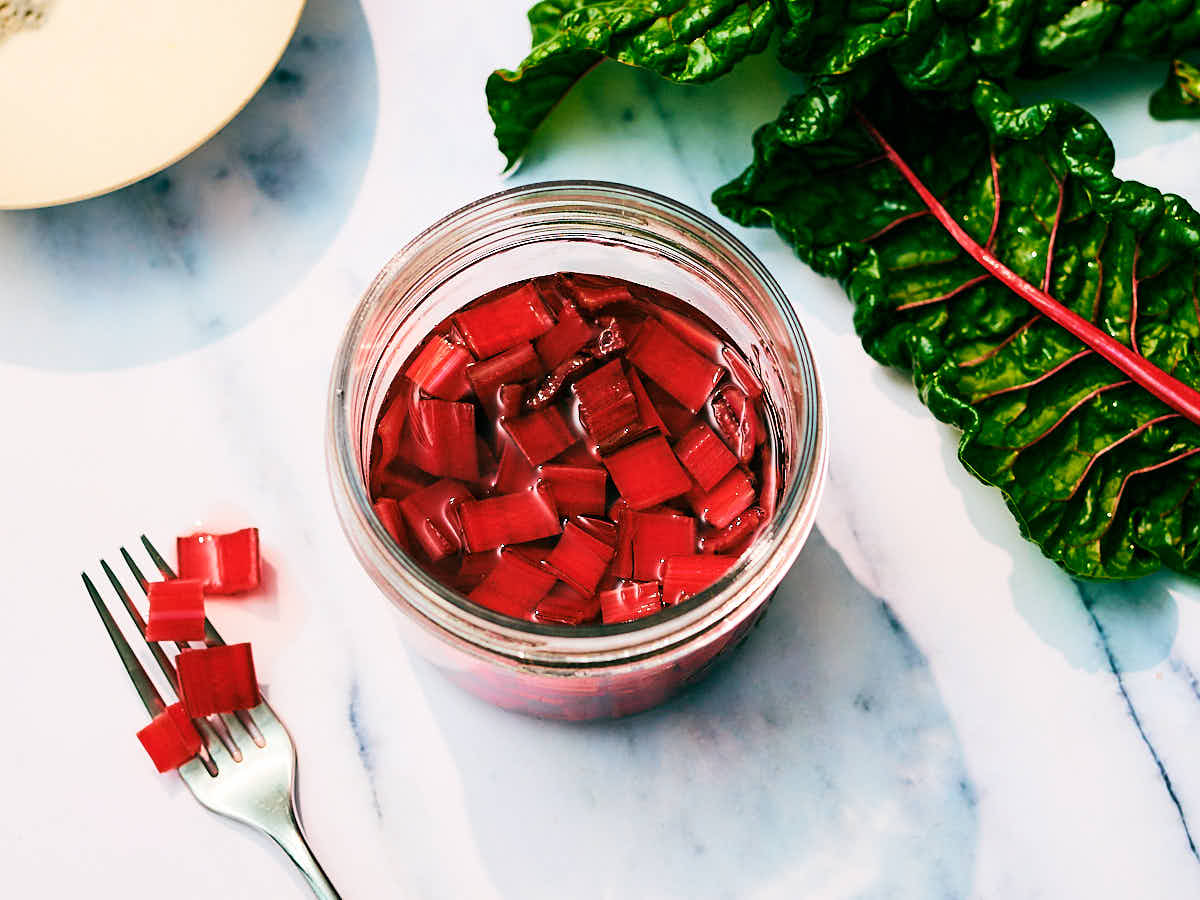 Easy Pickled Chard Stems in a glass jar and on a fork.