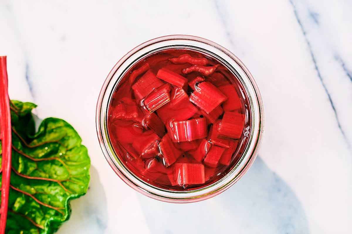 Quick Pickled Chard Stems marinating in a glass jar.
