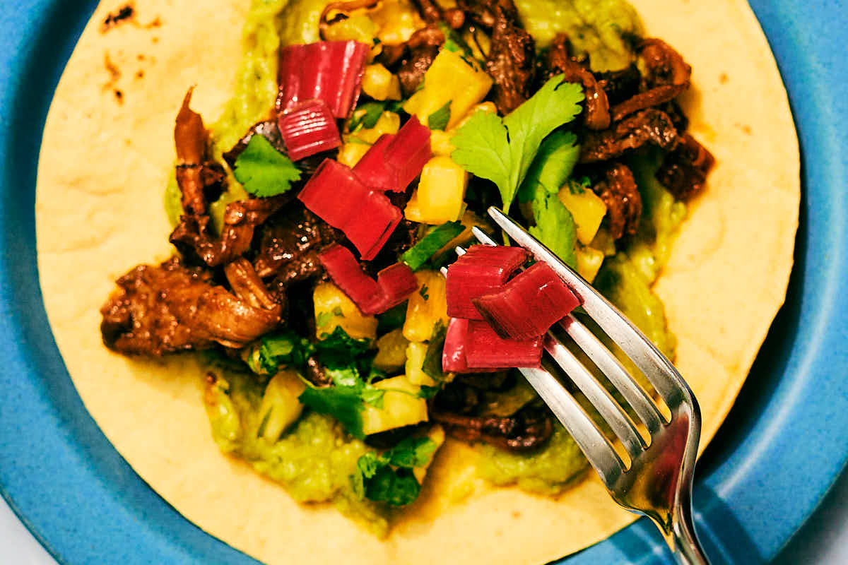 A fork scattering quick pickled chard stems on a taco.