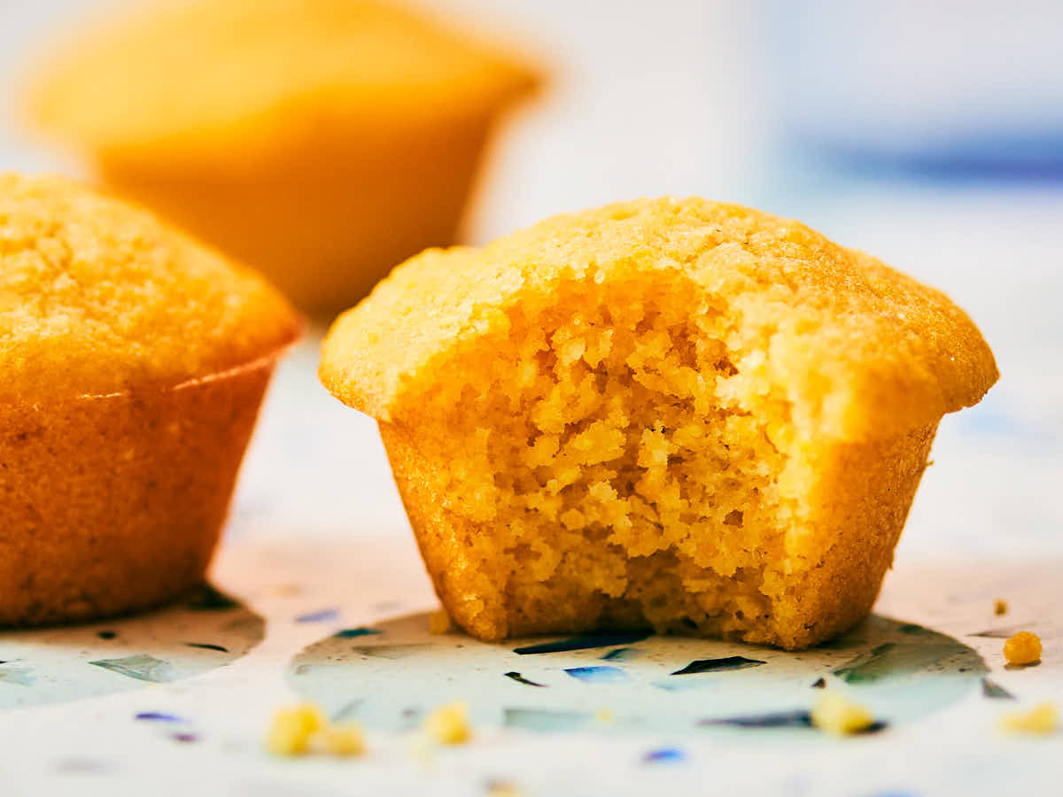 A moist mini cornbread muffin with a bite taken out of it.
