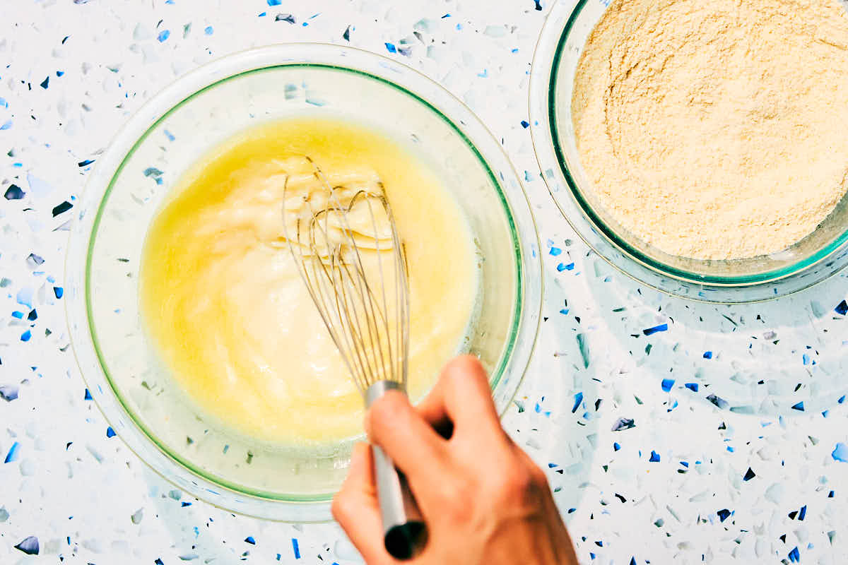 Wet and dry ingredients being whisked in separate bowls for cornbread.