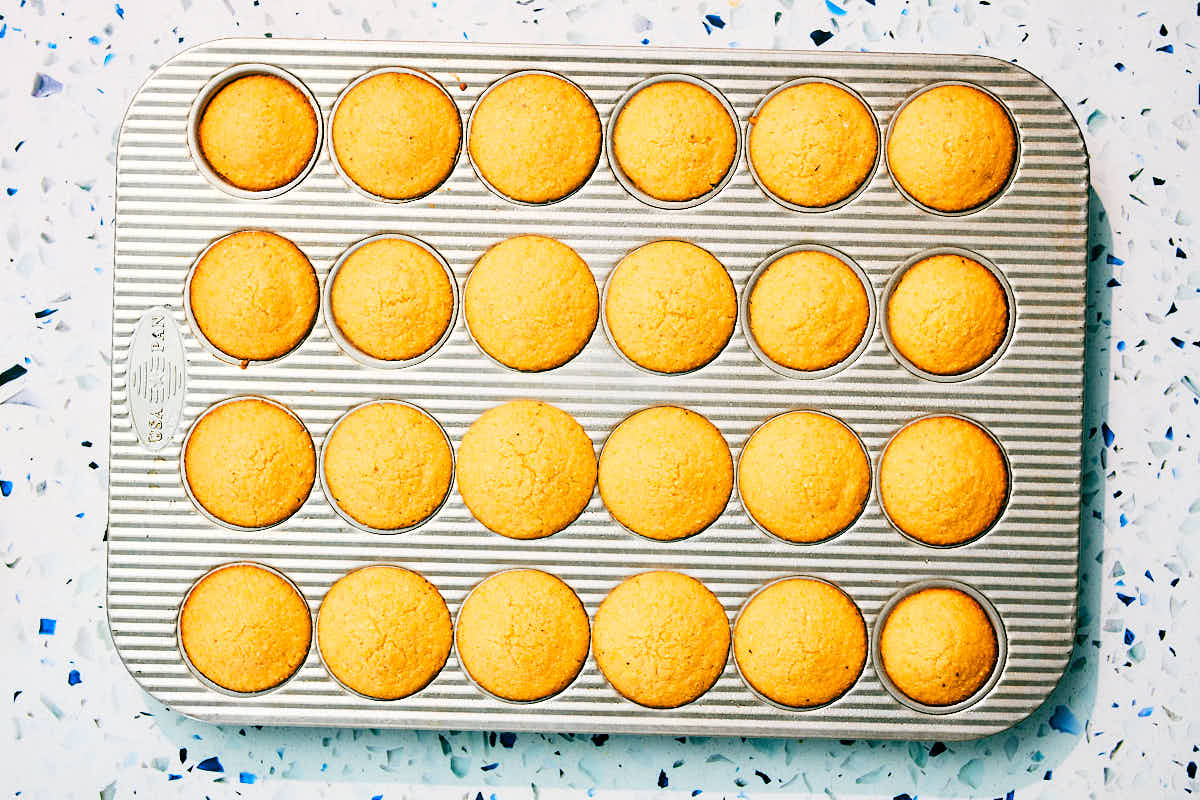 Mini cornbread muffins made without eggs in a muffin tin after baking.