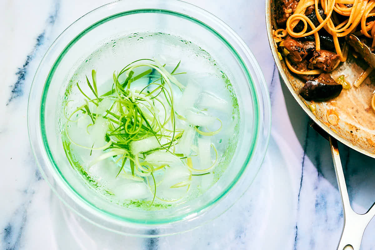 Scallion curls in a bowl of ice water.