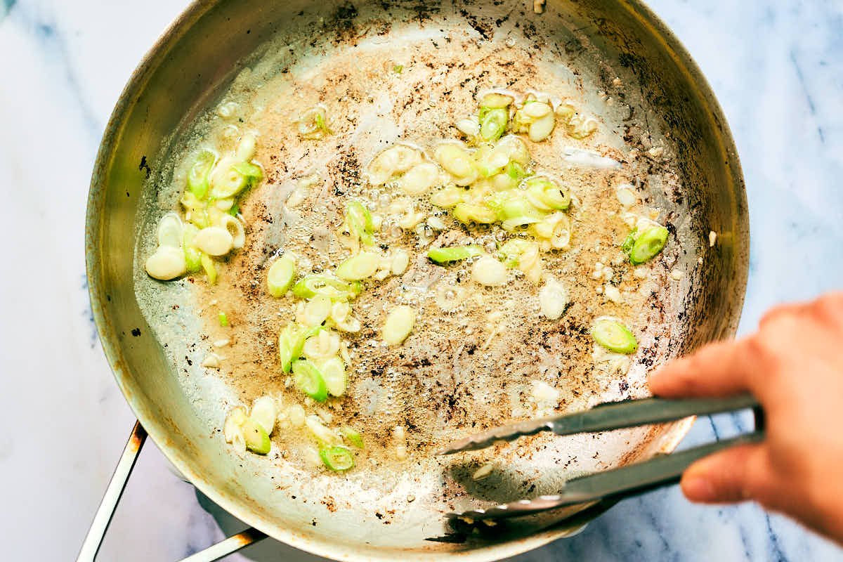 Butter, scallions and garlic sauteed in a skillet for Gochujang pasta.