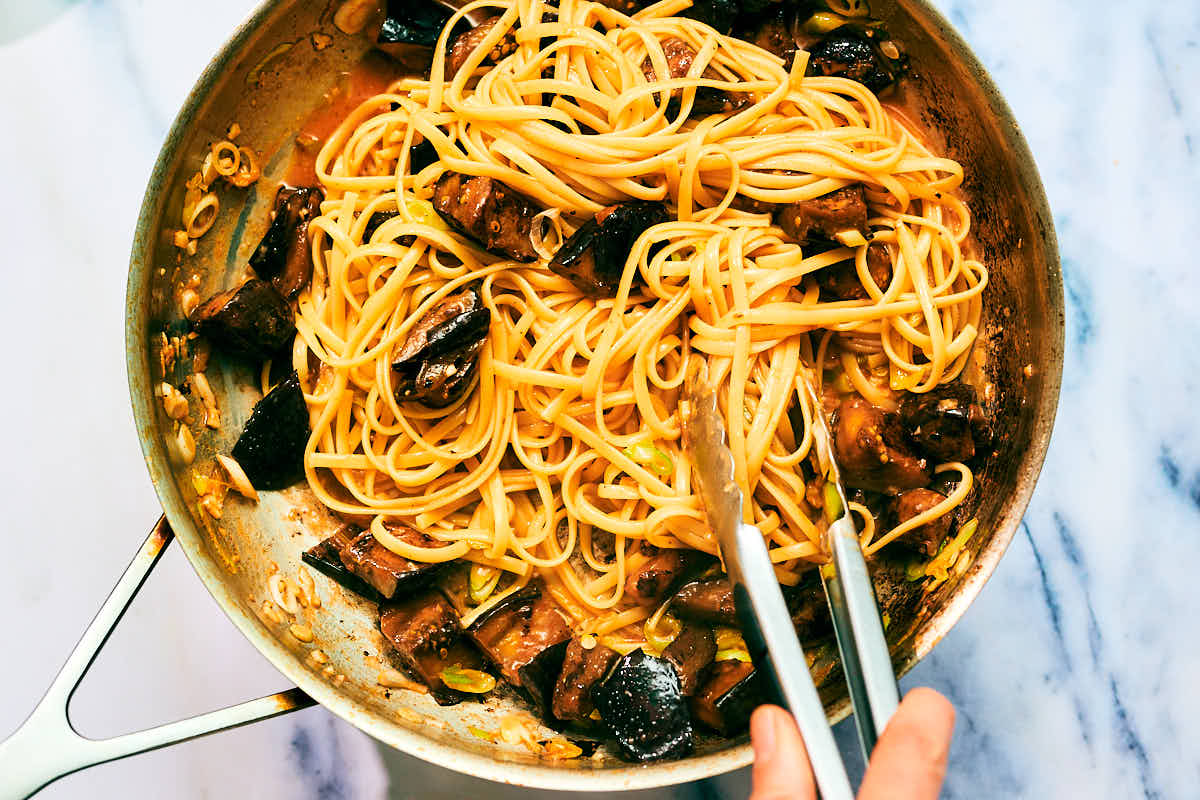 Gochujang Pasta being tossed with eggplant in a skillet.
