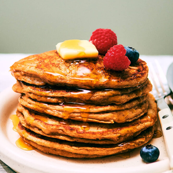 A stack of High Protein Cottage Cheese pancakes on a plate with berries.
