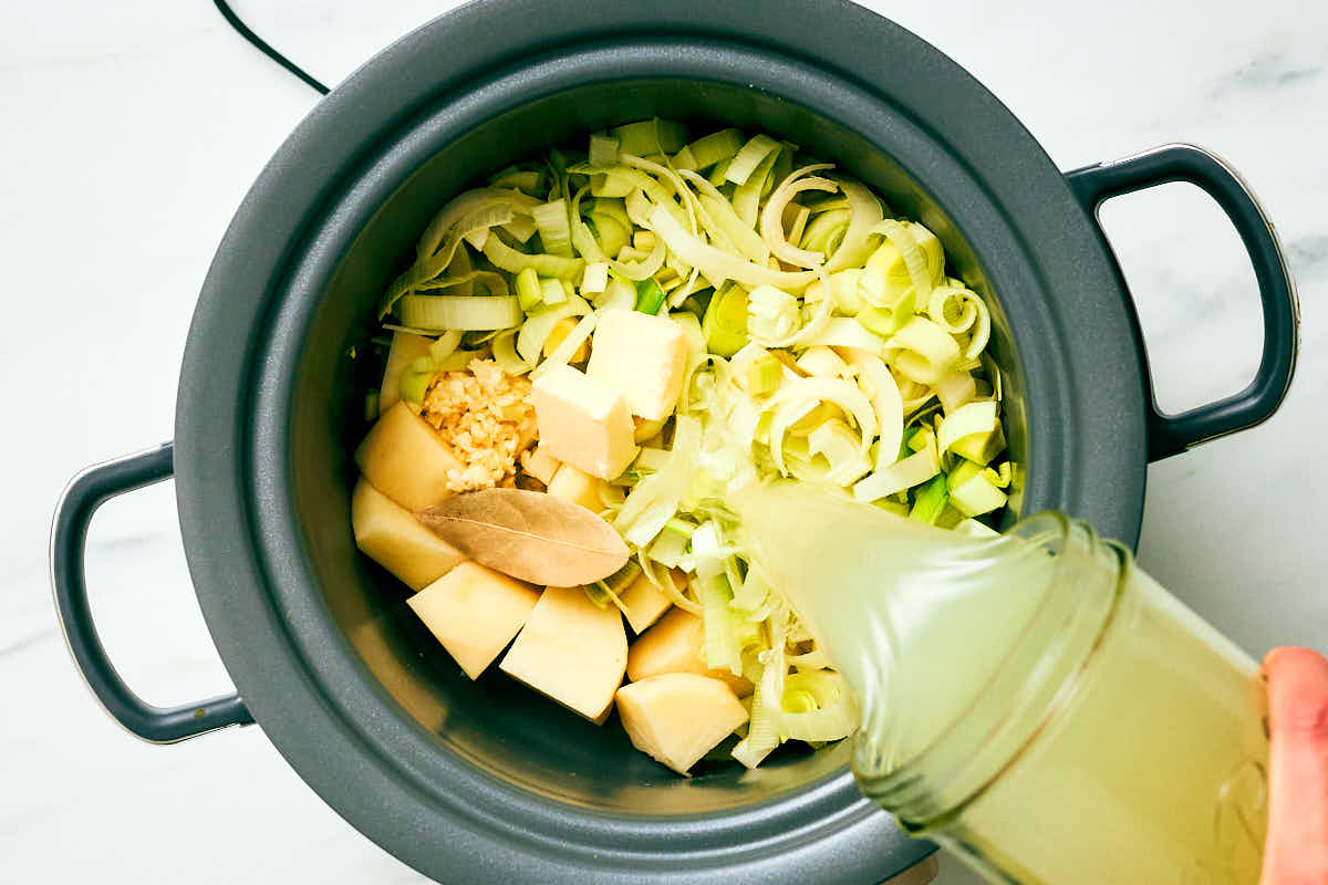 Ingredients for Potato Leek Soup being added to a slow cooker.