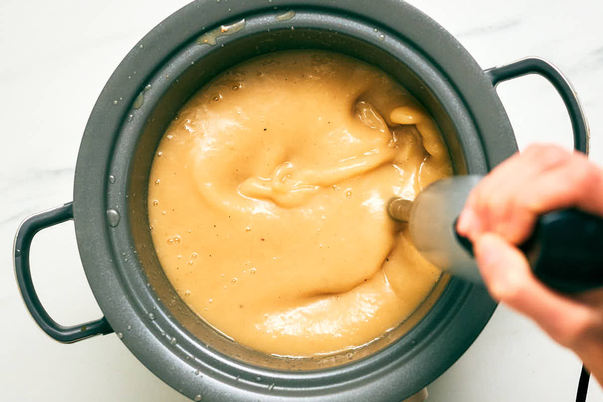 Easy Slow Cooker Potato Leek Soup being blended with an immersion blender.