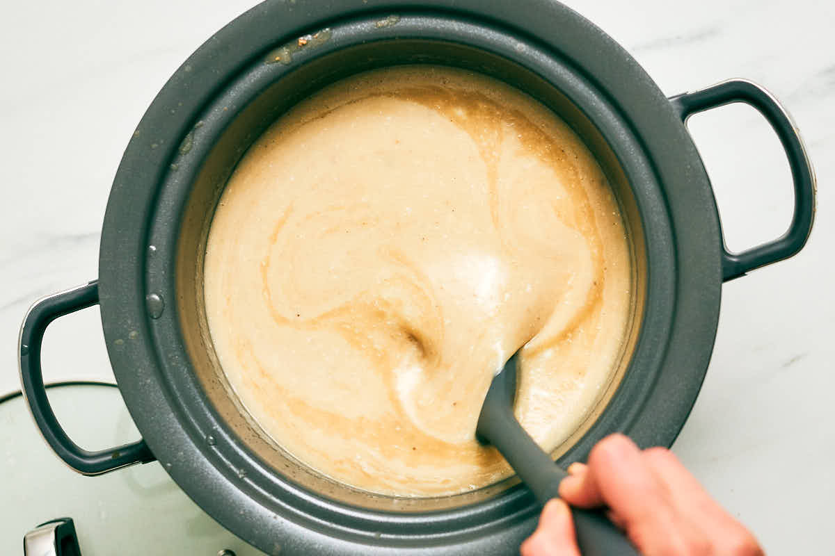 Buttermilk and cream being stirred into Potato Leek Soup in a slow cooker.