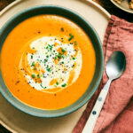 Slow Cooker Pumpkin Soup topped with cream and chives in a bowl.