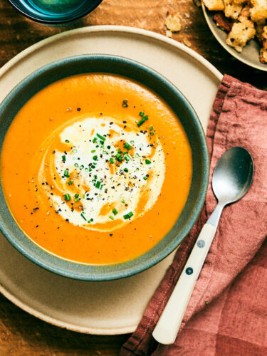 Slow Cooker Pumpkin Soup topped with cream and chives in a bowl.