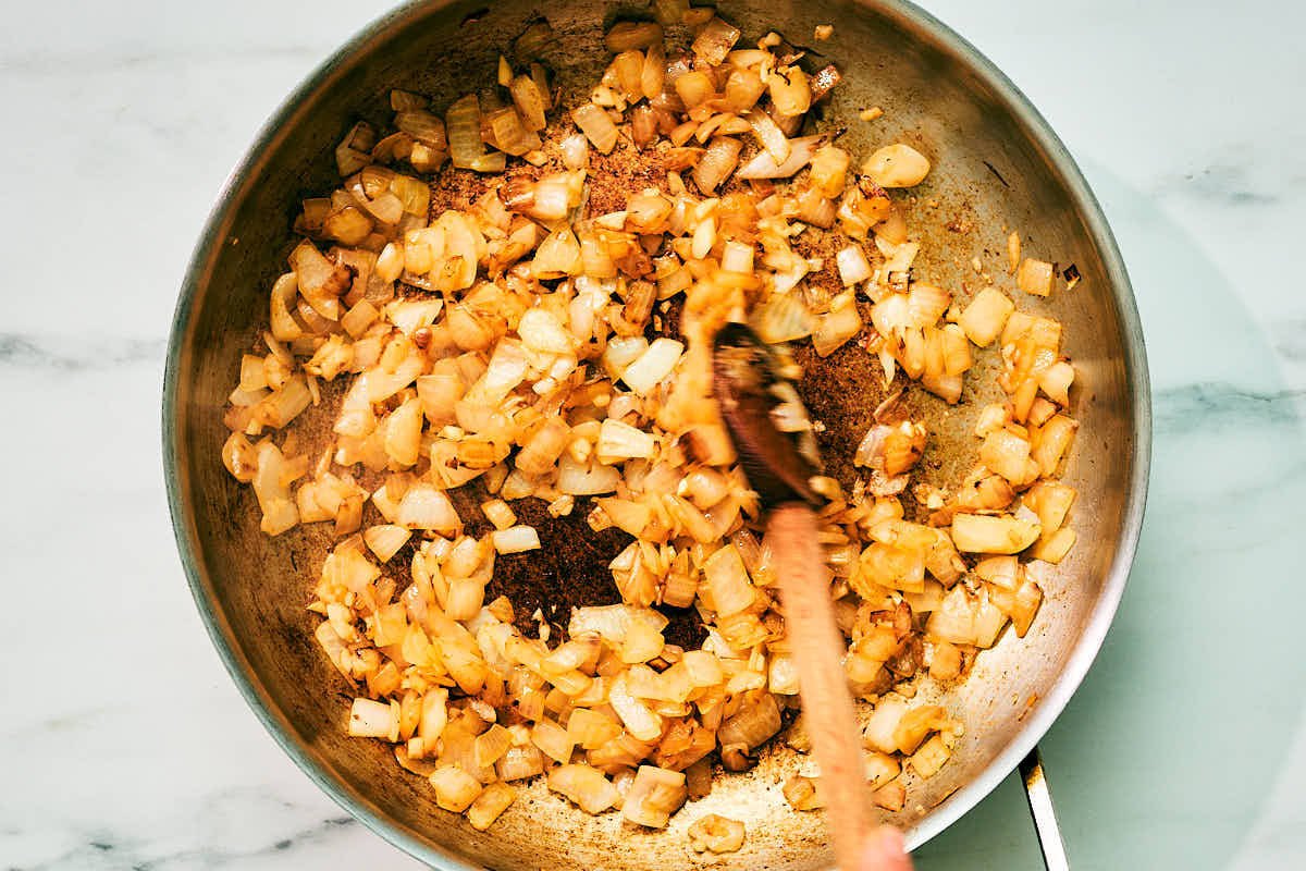 Onions and garlic being sauteed in skillet for pumpkin soup.