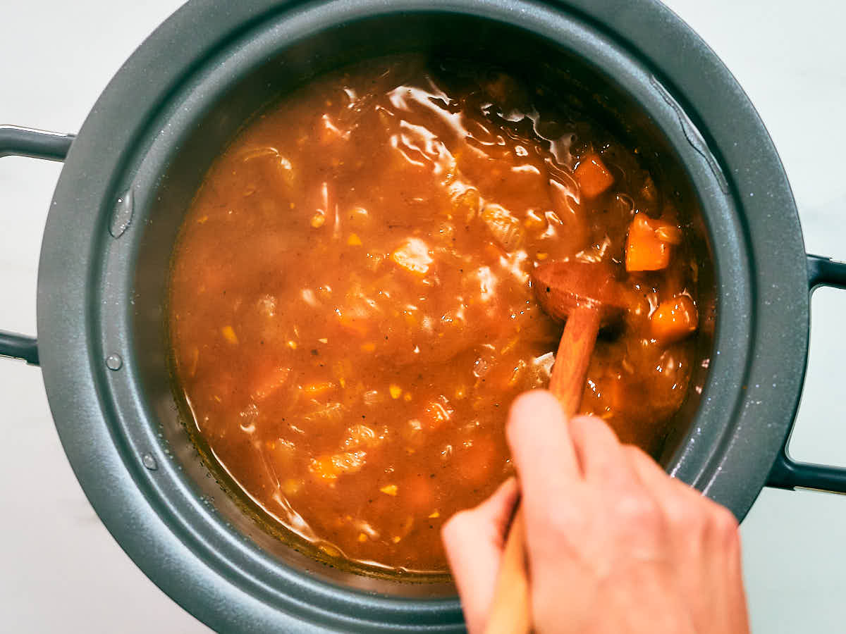Stirring pumpkin soup in a slow cooker, before blending.