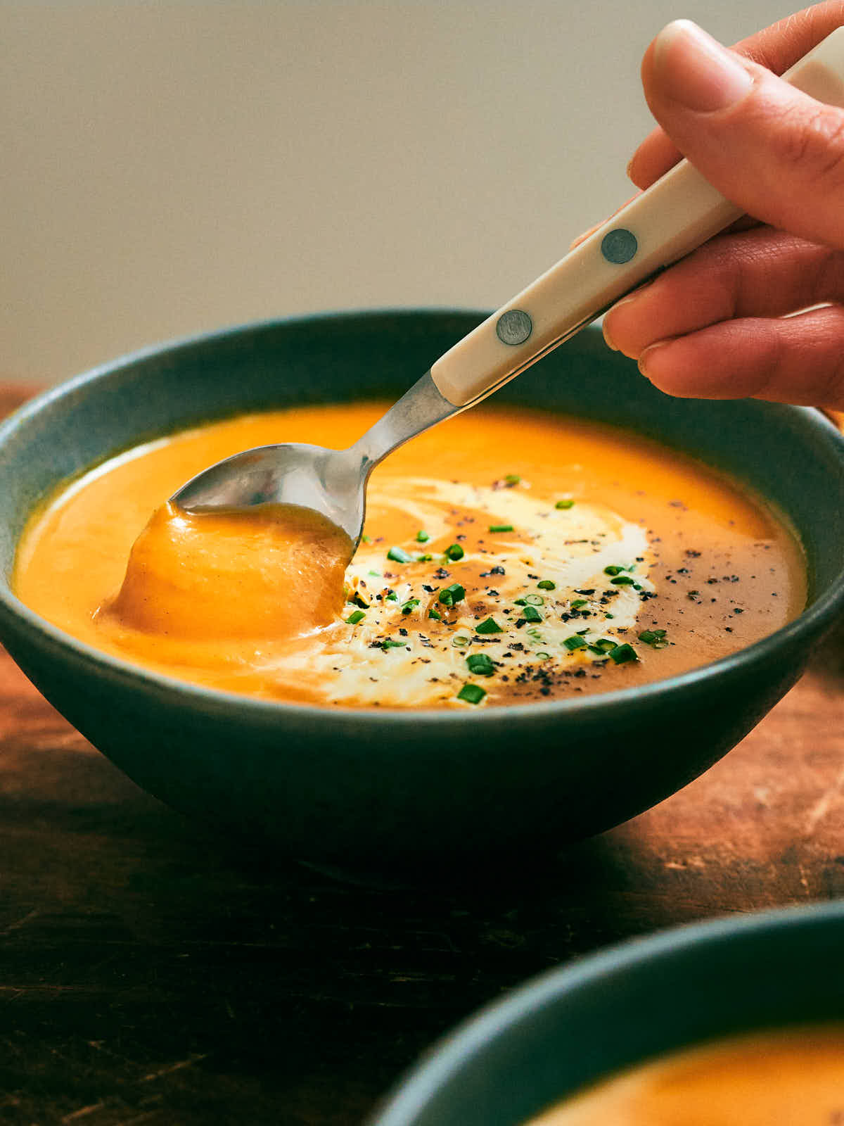 Creamy Slow Cooker Pumpkin Soup being spooned out of a bowl.