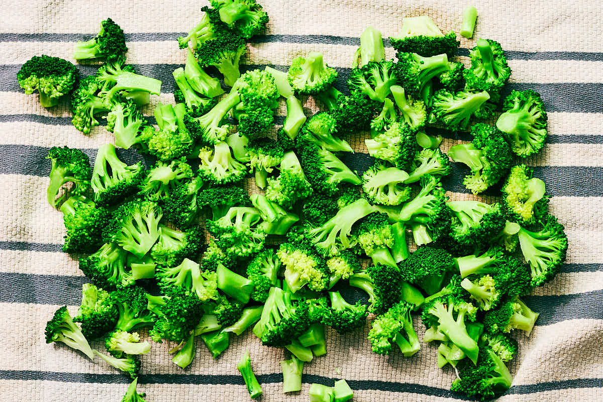 Blanched broccoli florets drying on a kitchen tea towel.