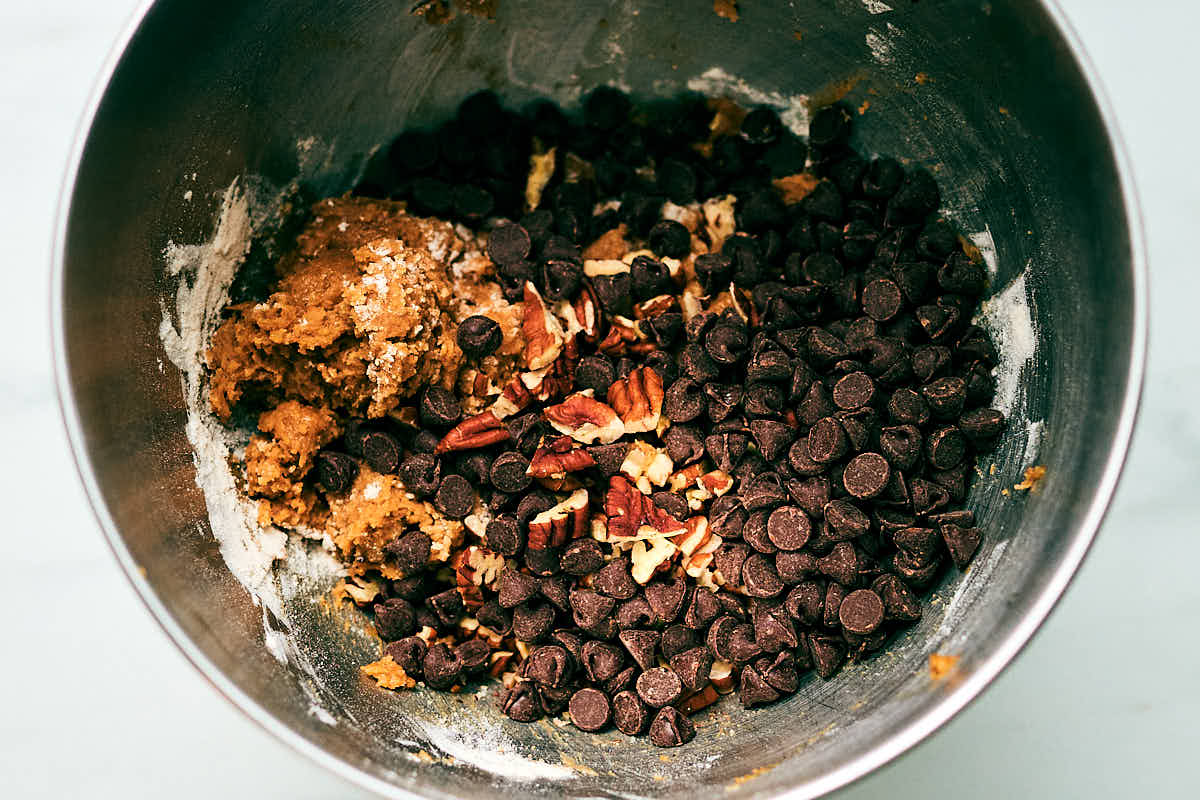Chocolate Chips and Pecans being added to cookie dough.