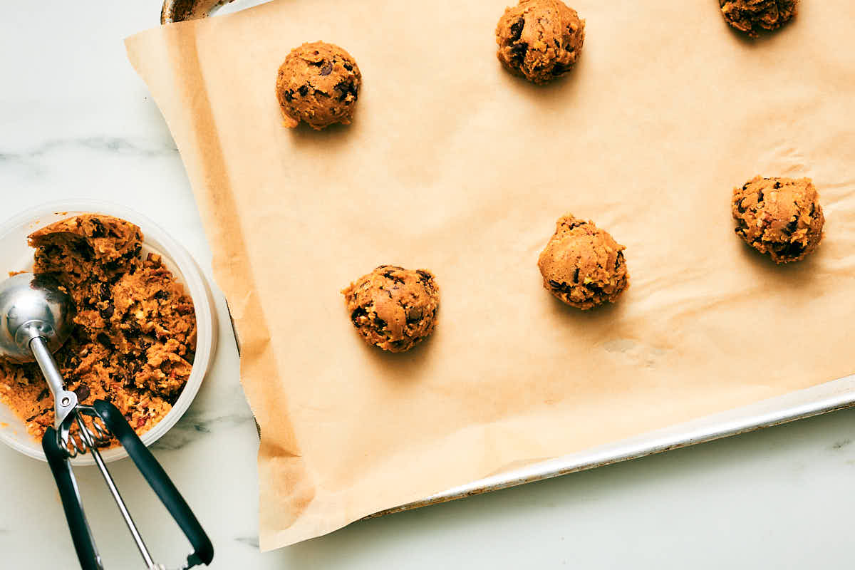 Pecan Chocolate Cookie dough balls on a parchment lined baking sheet before being baked.