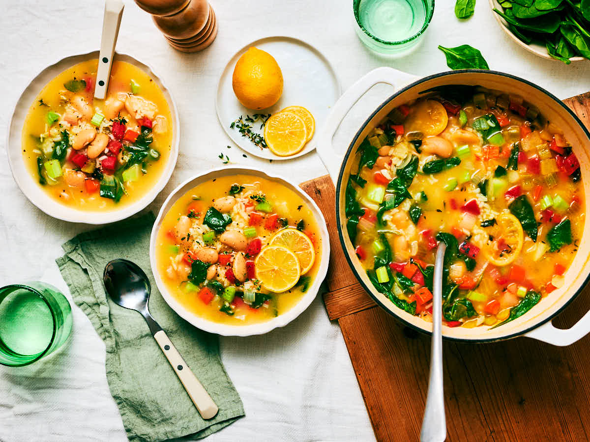 A pot and bowls of Lemon Rice and Bean Soup on a dinner table.