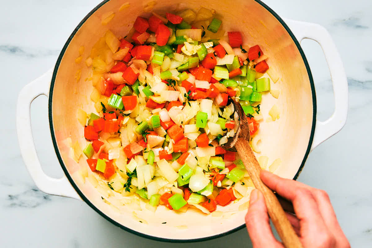Vegetables being sautéed in a pot for soup.