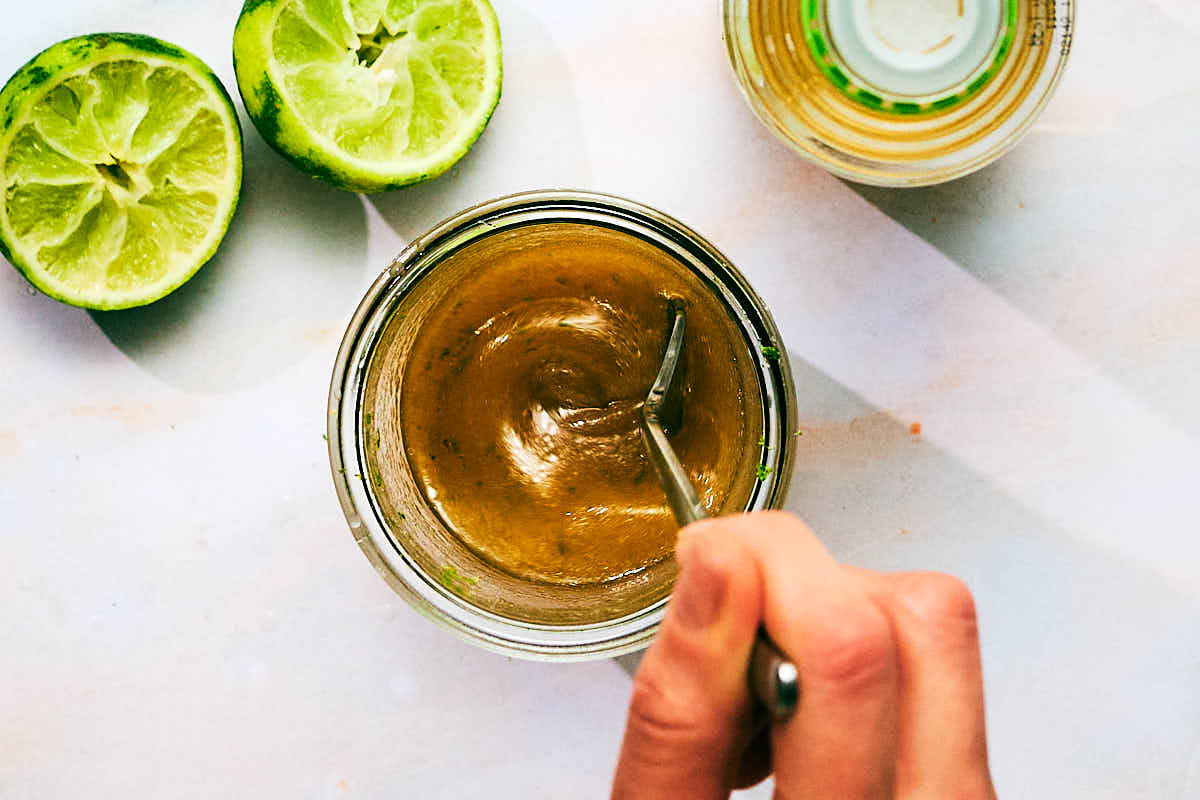 Lime vinaigrette being whisked in a glass jar for Asian Crunch Salad.