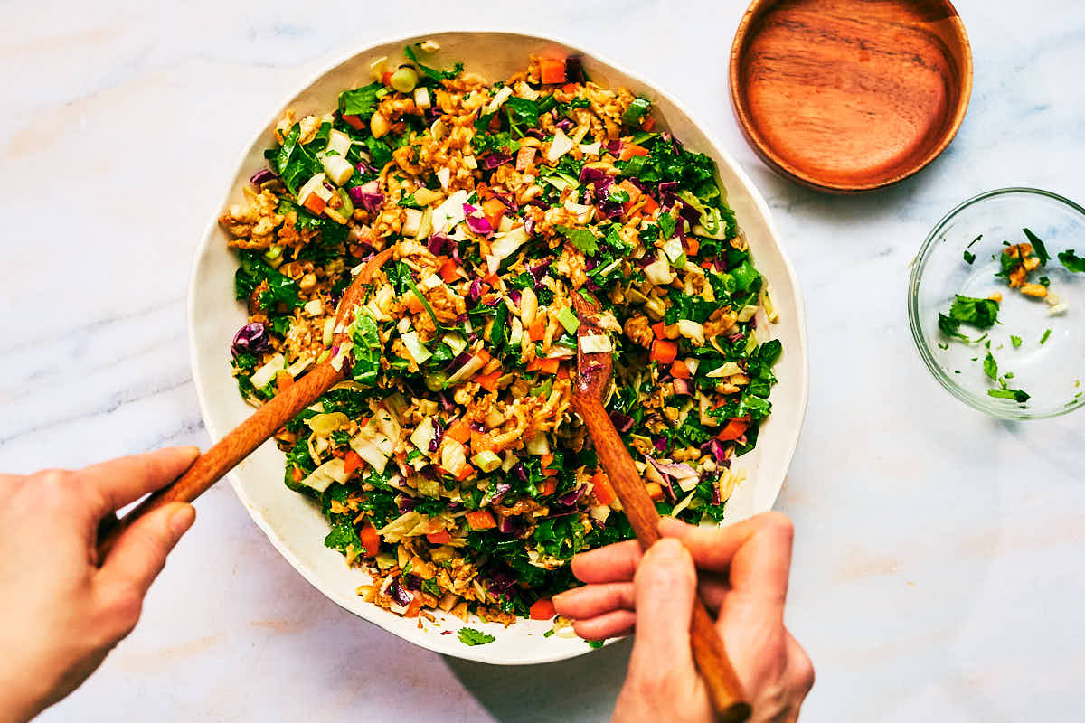 High protein Asian Crunch Salad being tossed in a salad bowl.