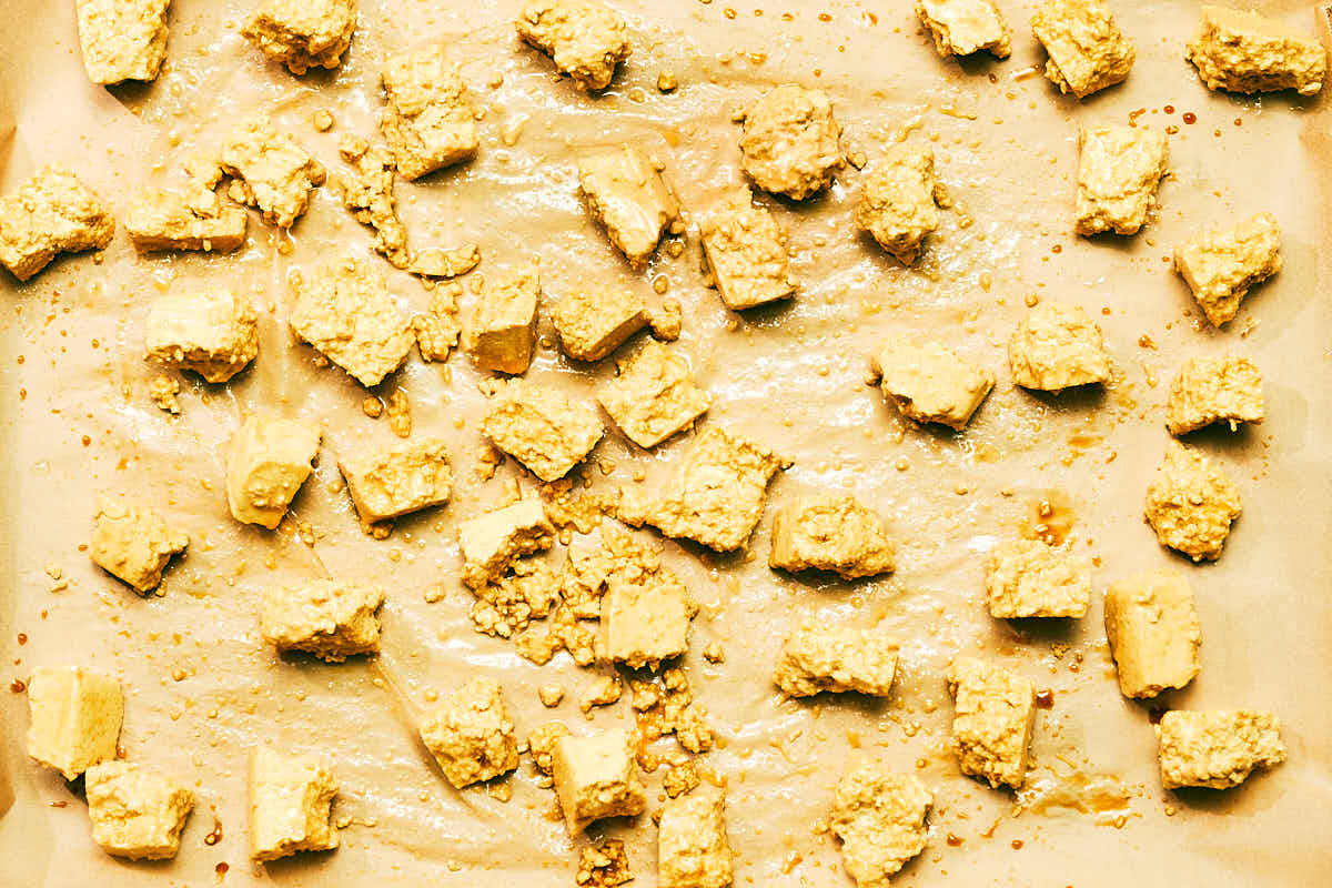 Tofu torn into cubes on a baking sheet.