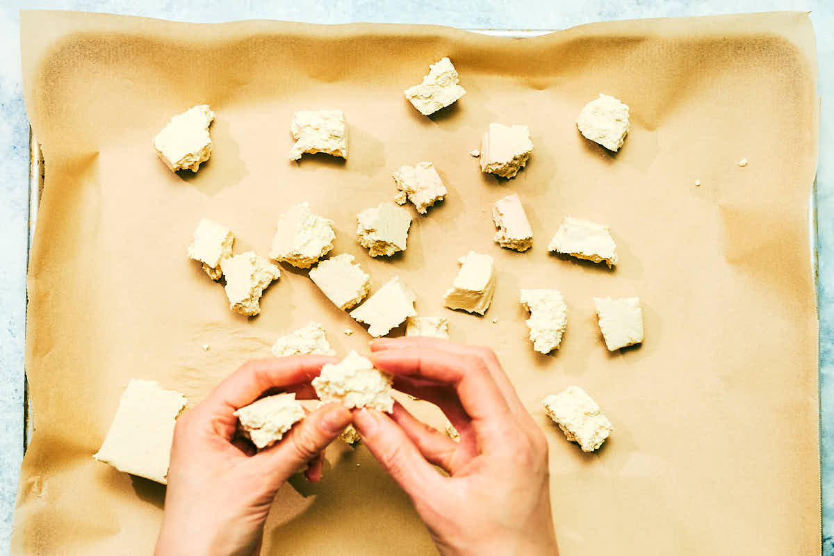 Extra firm tofu being torn into bite-sized pieces.