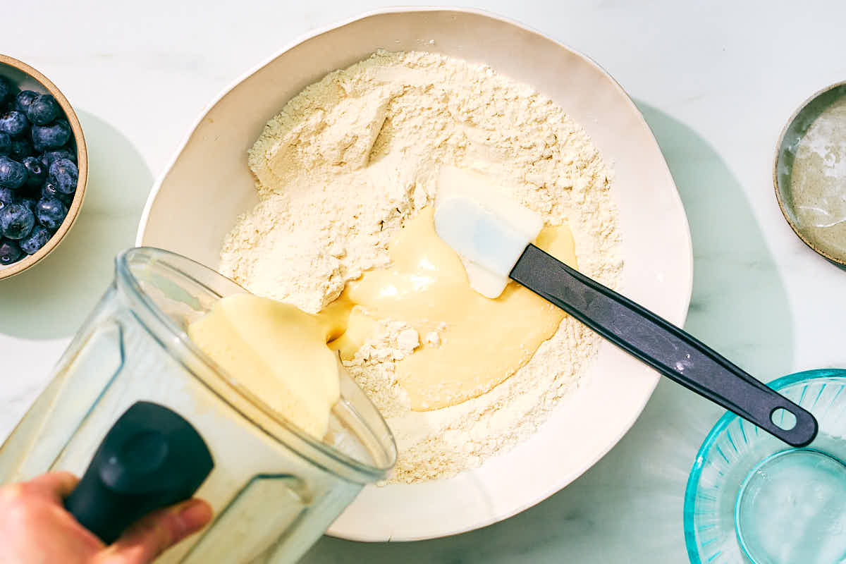 Pouring wet ingredients into bowl of dry ingredients for muffins.